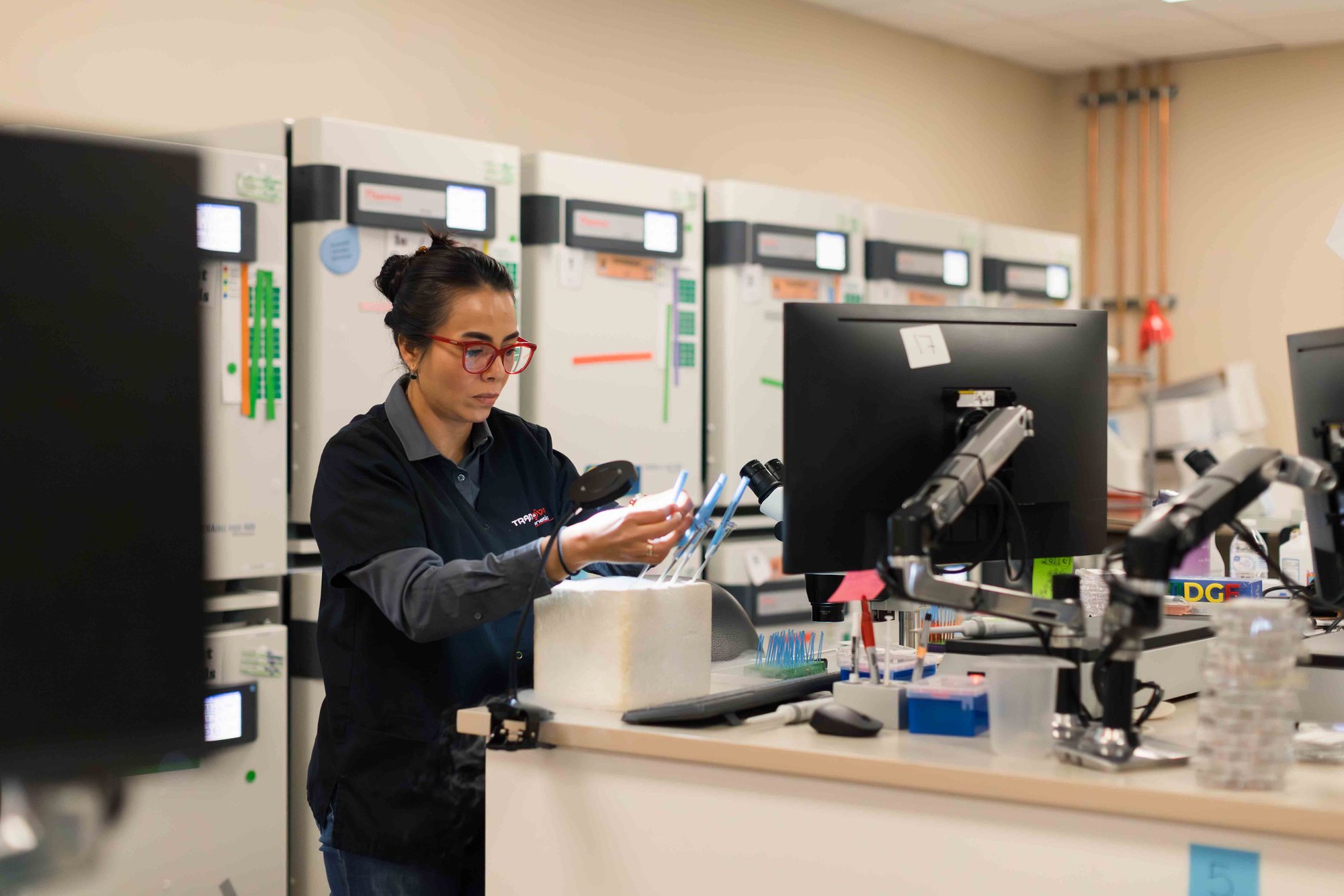 Lab technician handling samples at a workstation in a genetics laboratory.